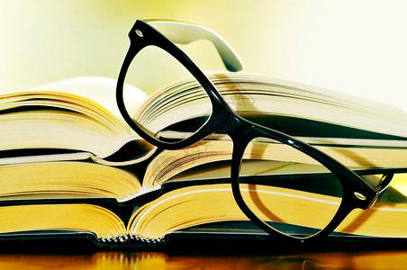 一堆象征阅读习惯或学习概念的书和眼镜图片素材
